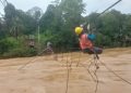 Petugas PLN saat membenahi jaringan kabel listrik yang terhantam banjir di atas jembatan gantung. (DETAIL/Daryanto)