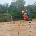 Petugas PLN saat membenahi jaringan kabel listrik yang terhantam banjir di atas jembatan gantung. (DETAIL/Daryanto)